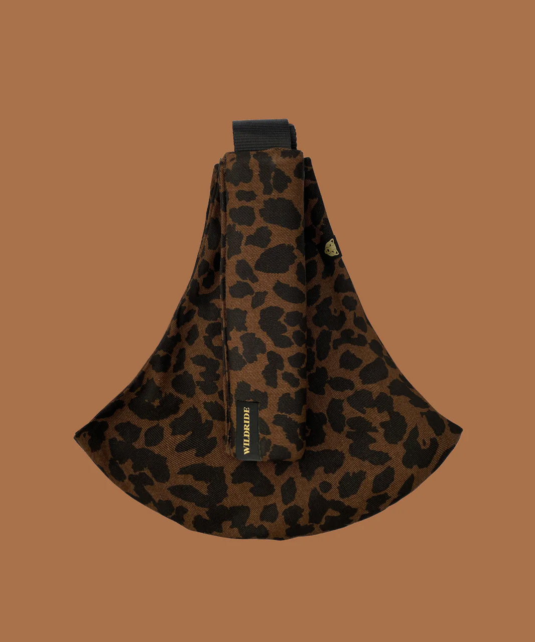 Wildride toddler carrier in brown leopard. A 100% cotton seat stylish hip carrier for babies showing the strap folded over the carrier seat.