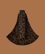 Wildride toddler carrier in brown leopard. A 100% cotton seat stylish hip carrier for babies showing the strap folded over the carrier seat.