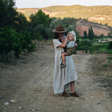 A woman carrying her child in the Wildride toddler carrier in a brown zebra print design