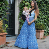 A woman in a long skirt holding her baby with support from the Wildride toddler hip sling carrier, in charcoal grey.