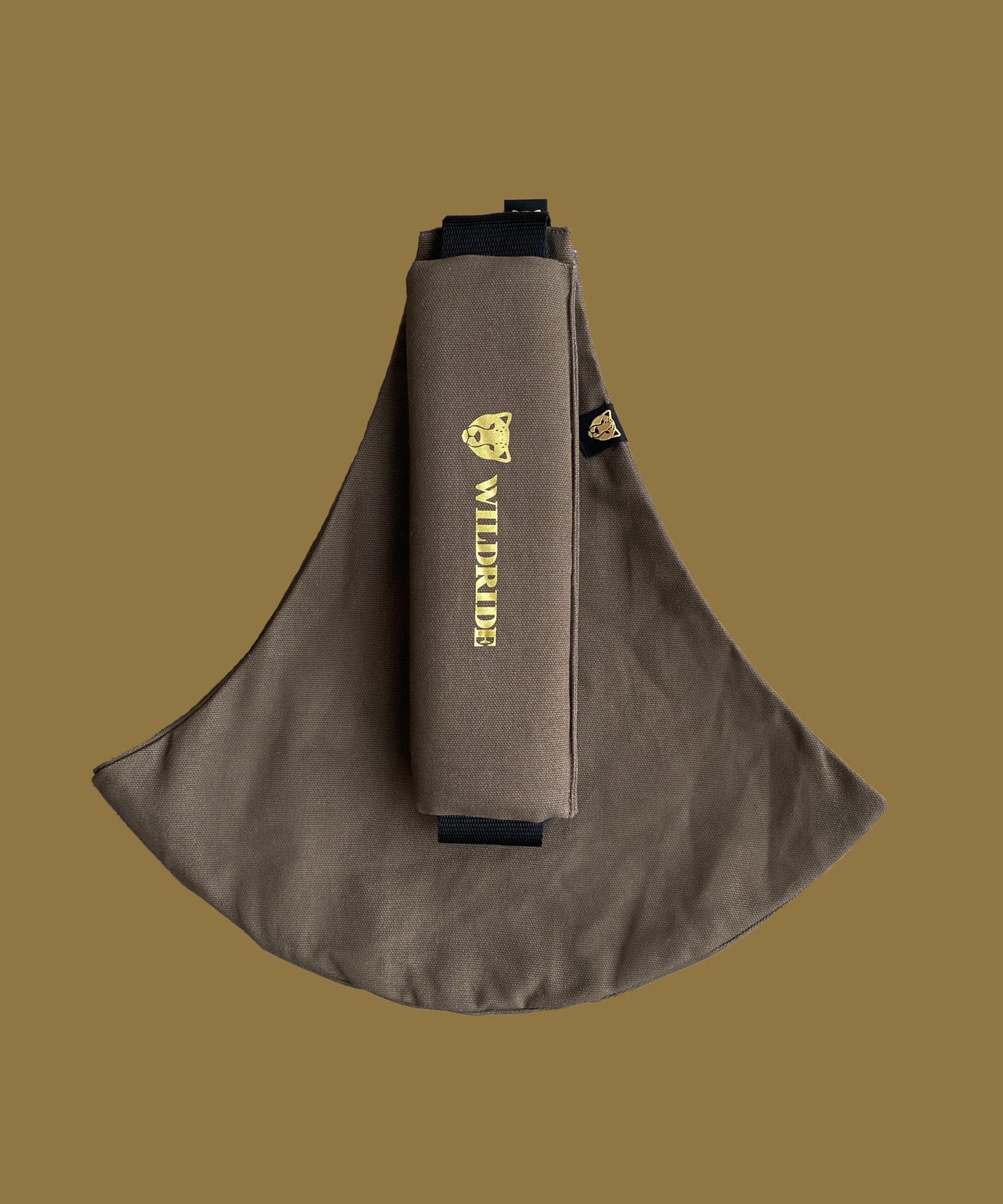 Wildride toddler carrier in coffee brown. A 100% cotton seat stylish hip carrier for babies with brand name on the strap that's folded over the carrier's seat