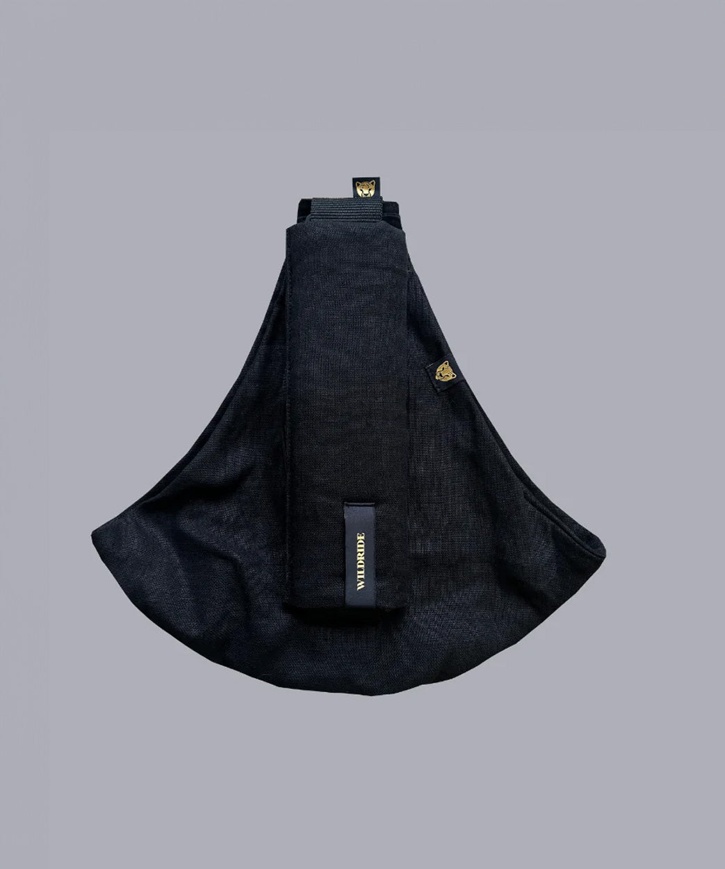 Wildride toddler carrier in black linen. A stylish hip carrier for babies with a black brand patch on the strap that's folded over the carrier's seat