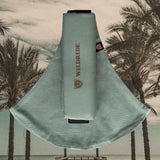 The Wildride fern green toddler carrier, on a background of palm trees