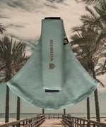 The Wildride fern green toddler carrier, on a background of palm trees