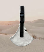 A side view of the sand linen Wildride toddler carrier showing the buckle and seat detail. Features a brand patch on the buckle.