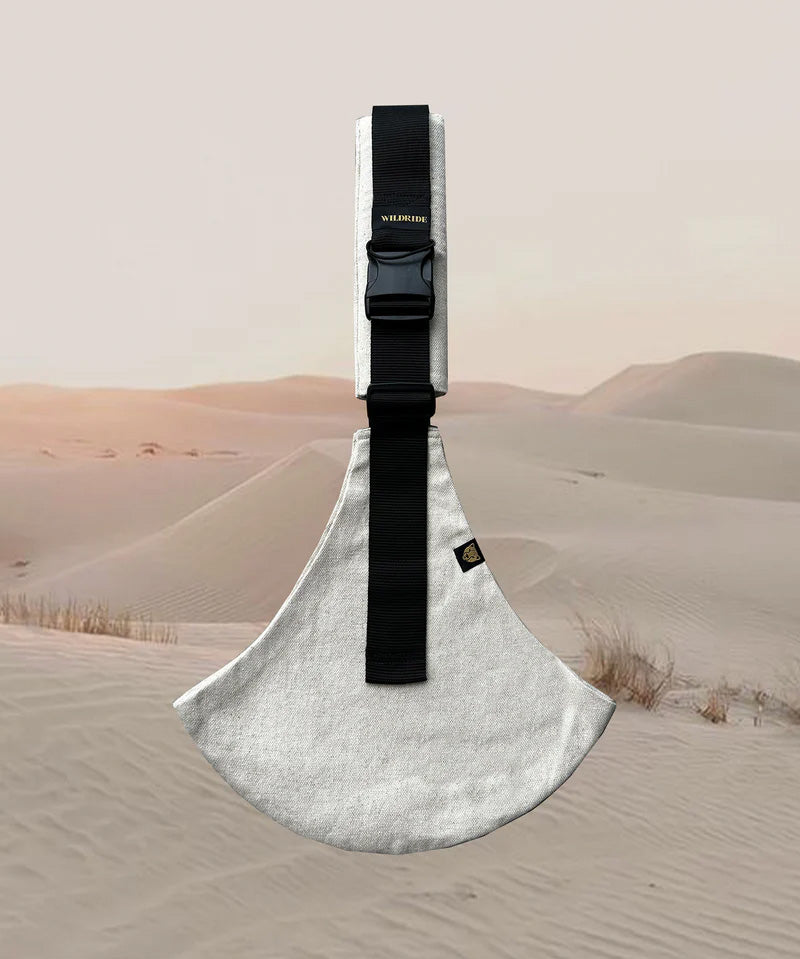 A side view of the sand linen Wildride toddler carrier showing the buckle and seat detail. Features a brand patch on the buckle.