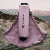 Wildride toddler carrier in vintage rose. A 100% cotton seat stylish hip carrier for babies with brand name in brown on the strap that's folded over the carrier's seat with a mountain scape in the background.
