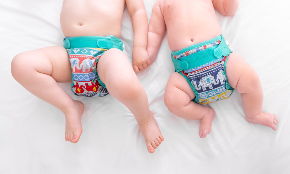 Two babies lay on a bed wearing Babipur x Close Pop In reusable cloth nappies to represent 'Reusable Nappies For A Heavy WetterReusable Nappies For A Heavy Wetter' blog by Babipur.