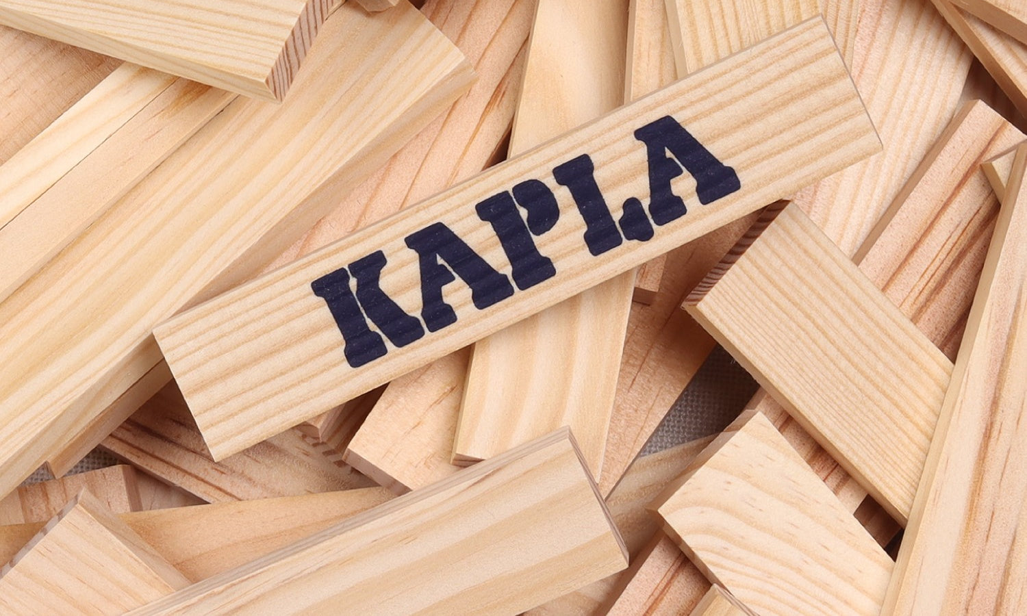Kapla building blocks, natural pine wood blocks of a uniform shape and size. Central block branded with KAPLA