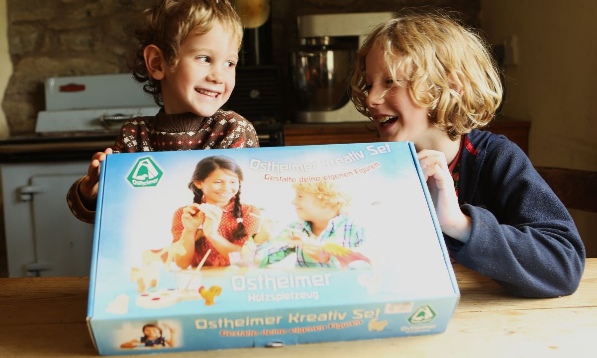 Two children hold up the Ostheimer Creative Painting Set at a kitchen table