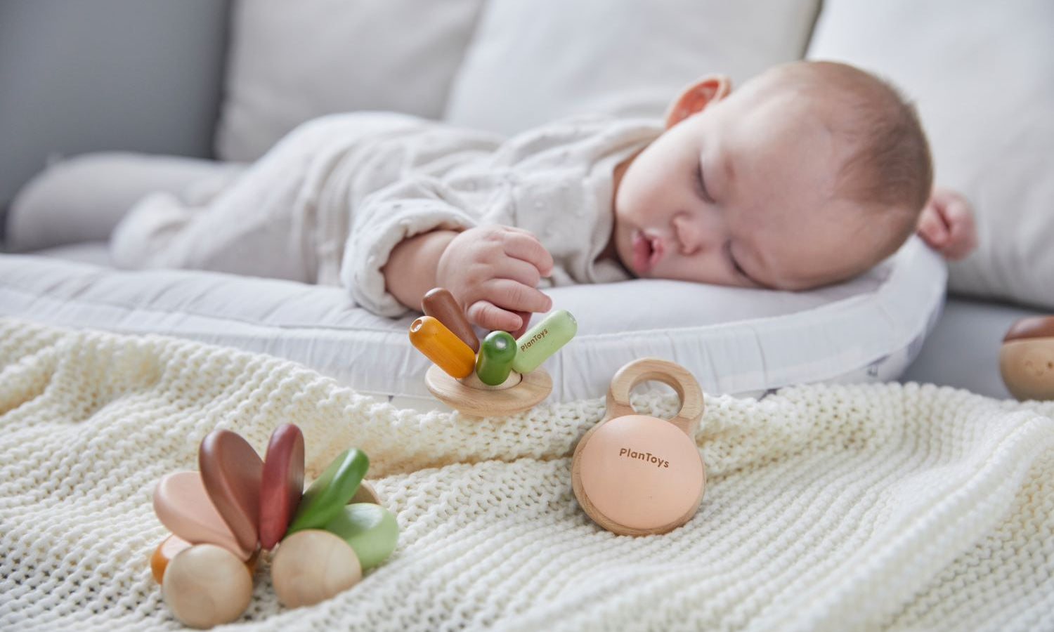 A baby fast asleep grasping the PlanToys Flexi Jellyfish Grasping Toy