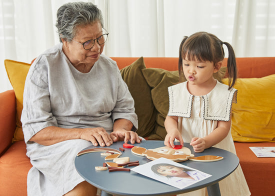 Image of elderly woman and young girl playing with a 'Build a Face' wooden toy