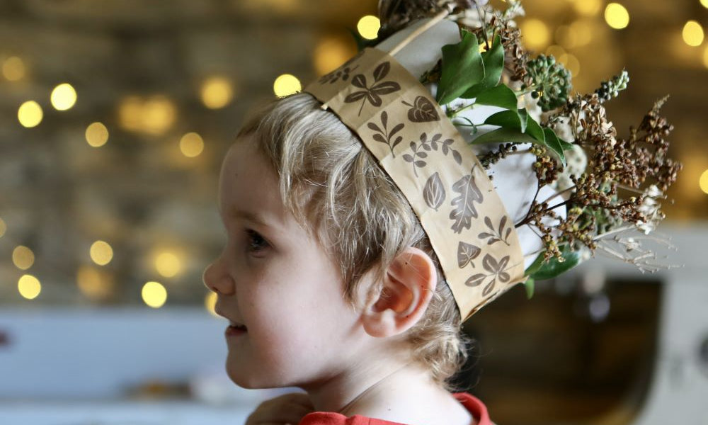 Child wearing a Winter Crown, a winter craft for kids made using paper tape, recycled card and dried seed heads