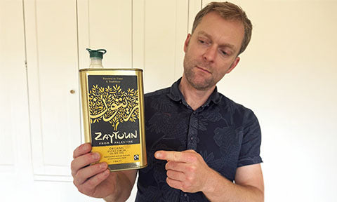 Peter from babipur holds a tin of Zaytoun Palestinian Olive Oil and points at the Fiartrade label