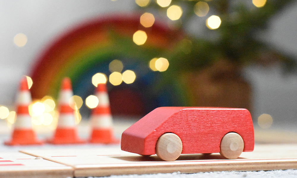 Beck wooden Toy car on the Beck wooden road with toy traffic cones in background and sparkly lights