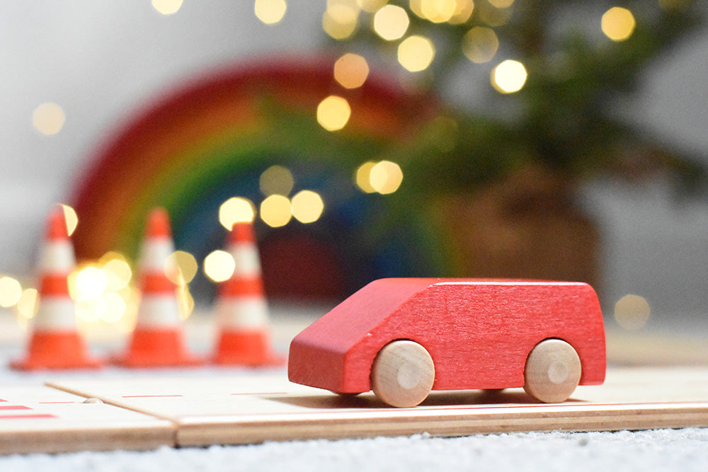 Beck wooden Toy car on the Beck wooden road with toy traffic cones in background and sparkly lights