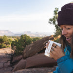 A collection of Kleen Kanteen 12oz Camping Mugs stacked on top of a rock