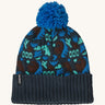 A blue Patagonia bobble beanie with different shapes and patterns on a cream background.