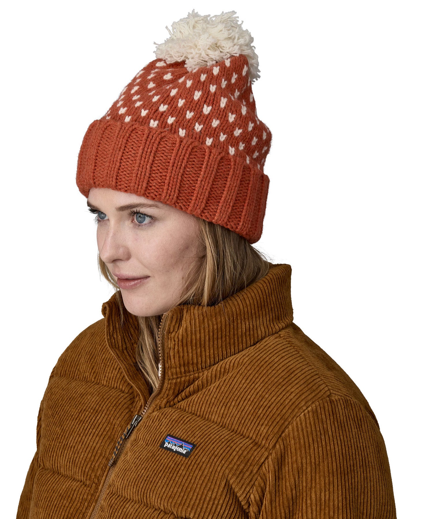 A female adult wearing the red Patagonia  beanie with a cream pompom 