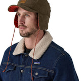 A male adult wearing the brown Patagonia earflap cap with the flaps down.