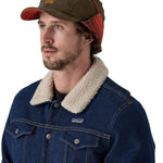 A male adult wearing the brown Patagonia earflap cap with the flaps tied up.
