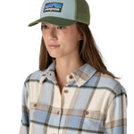 A female adult wearing the light blue and green Patagonia trucker hat