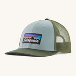  A light blue and green Patagonia trucker hat with the Patagonia logo on the front on a cream background. 