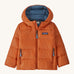 Orange kids Patagonia down jacket on a cream background