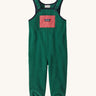 Green baby overalls on a cream background