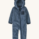 Dark blue fluffy kids all in one with little ears on the hood on a cream background