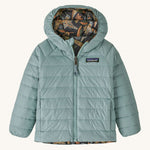 Light green with reversible bird print Patagonia down jacket on a cream background
