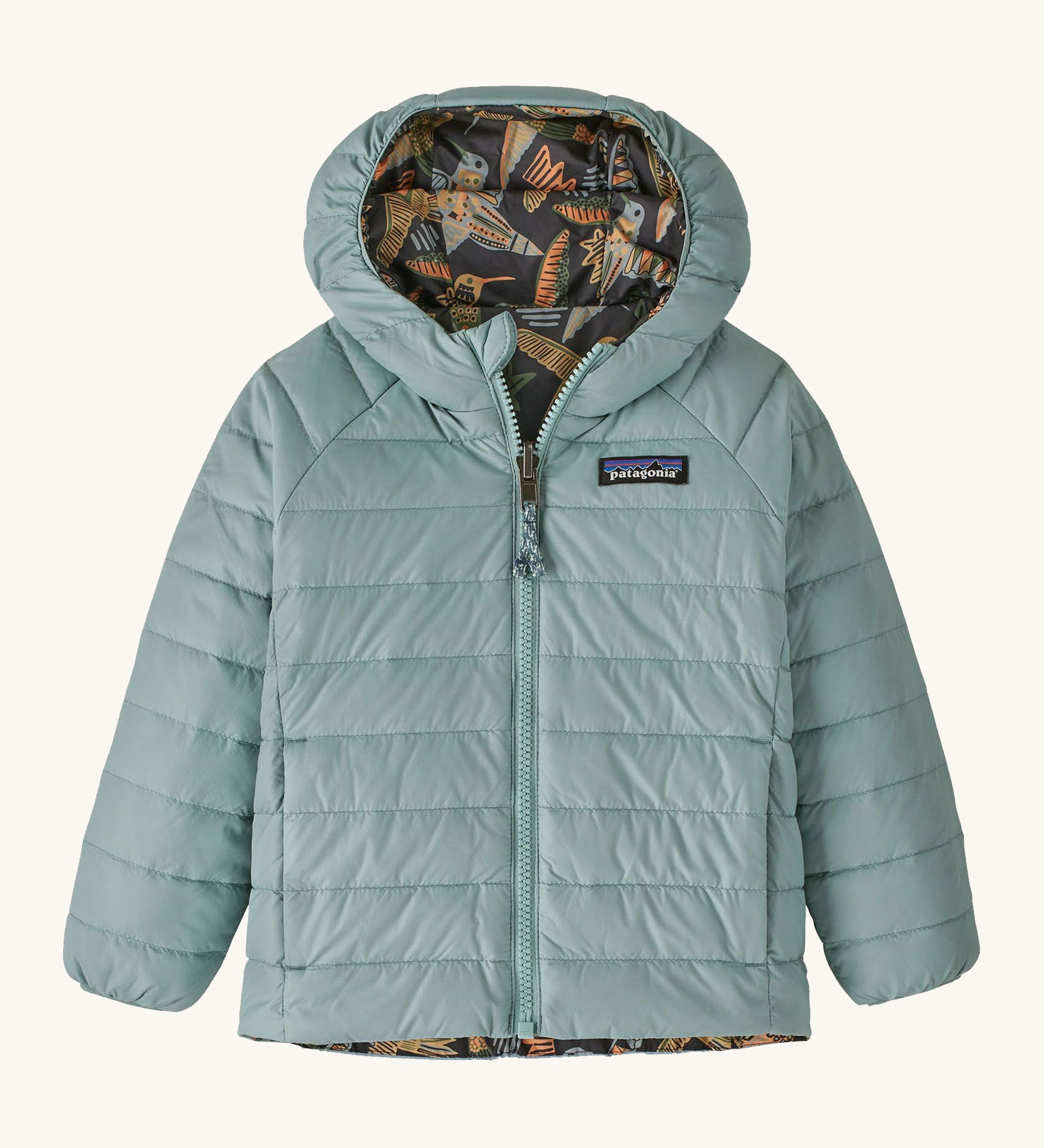 Light green with reversible bird print Patagonia down jacket on a cream background