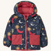 Navy Patagonia reversible jacket with a moon and stars design and red pockets on a cream background