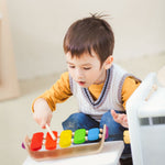 Child playing with the Plan Toys Oval Xylophone with rainbow keys and made from natural rubber wood.