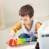 Child playing with the Plan Toys Oval Xylophone with rainbow keys and made from natural rubber wood.