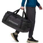 A person carrying the Patagonia Black Hole Duffel 70L Black with the carry handles