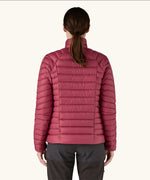 Back of woman wearing Patagonia down sweater puffer jacket in Marion Red, falling at the hips with a tight/slim fit. 