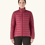 Woman wearing Patagonia recycled down puffer seater jacket in Marion Red. It falls at the hips and has a slim fit. 
