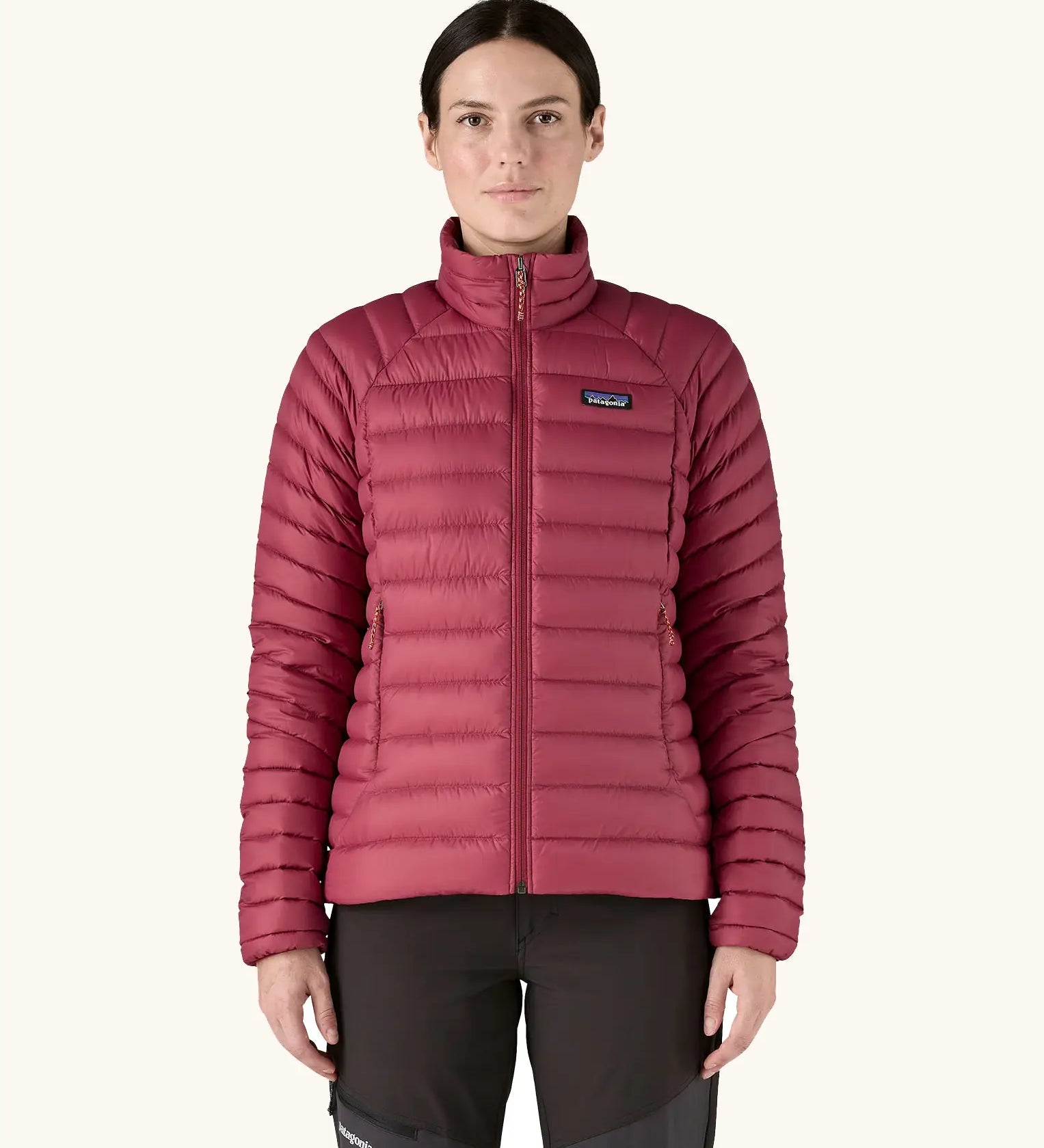 Woman wearing Patagonia recycled down puffer seater jacket in Marion Red. It falls at the hips and has a slim fit. 
