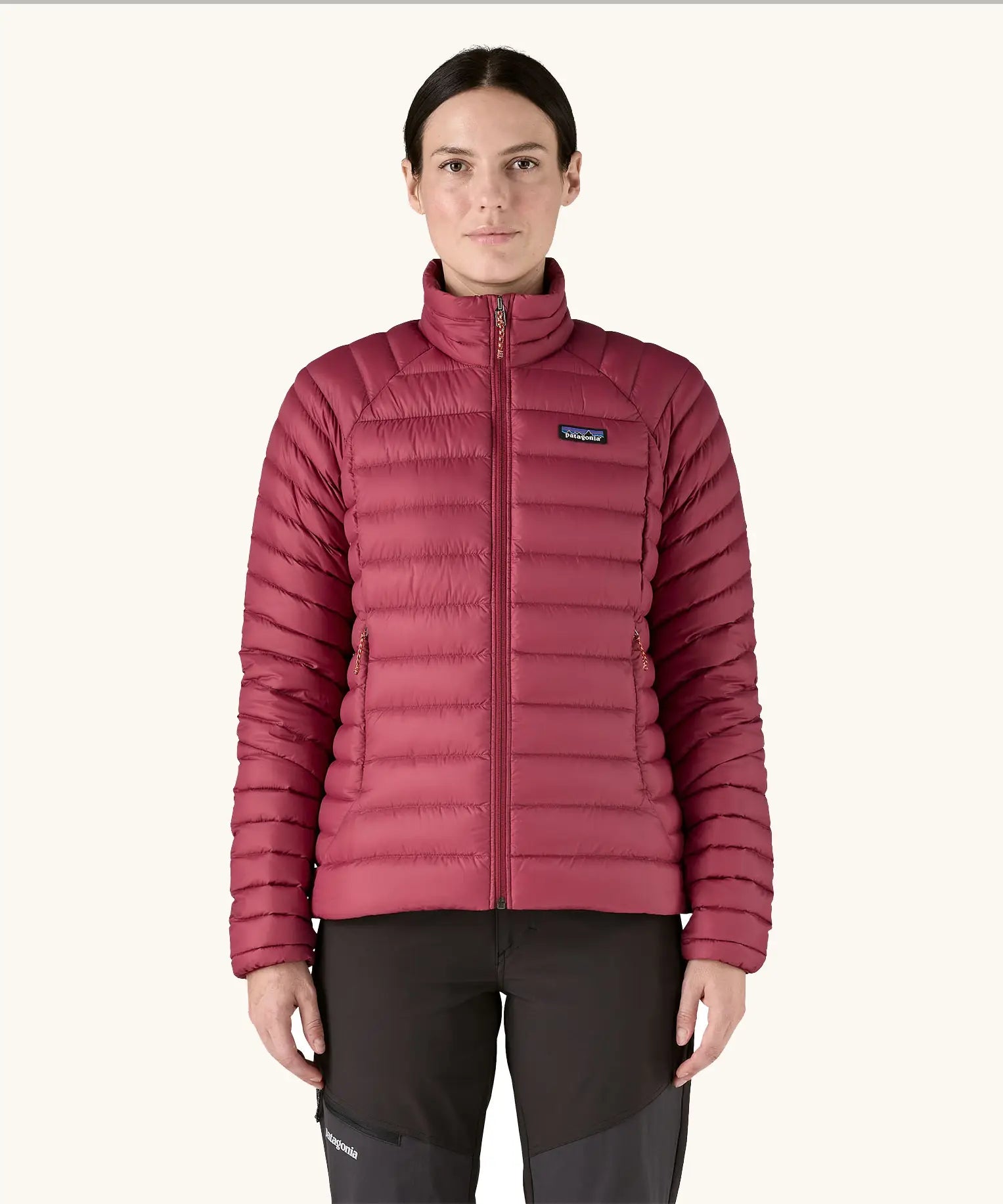 Woman wearing Patagonia recycled down puffer seater jacket in Marion Red. It falls at the hips and has a slim fit. 