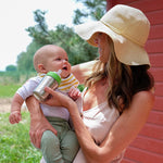 Woman feeding a baby with the Kid Kanteen 9oz metal baby bottle in front of a red wooden fence