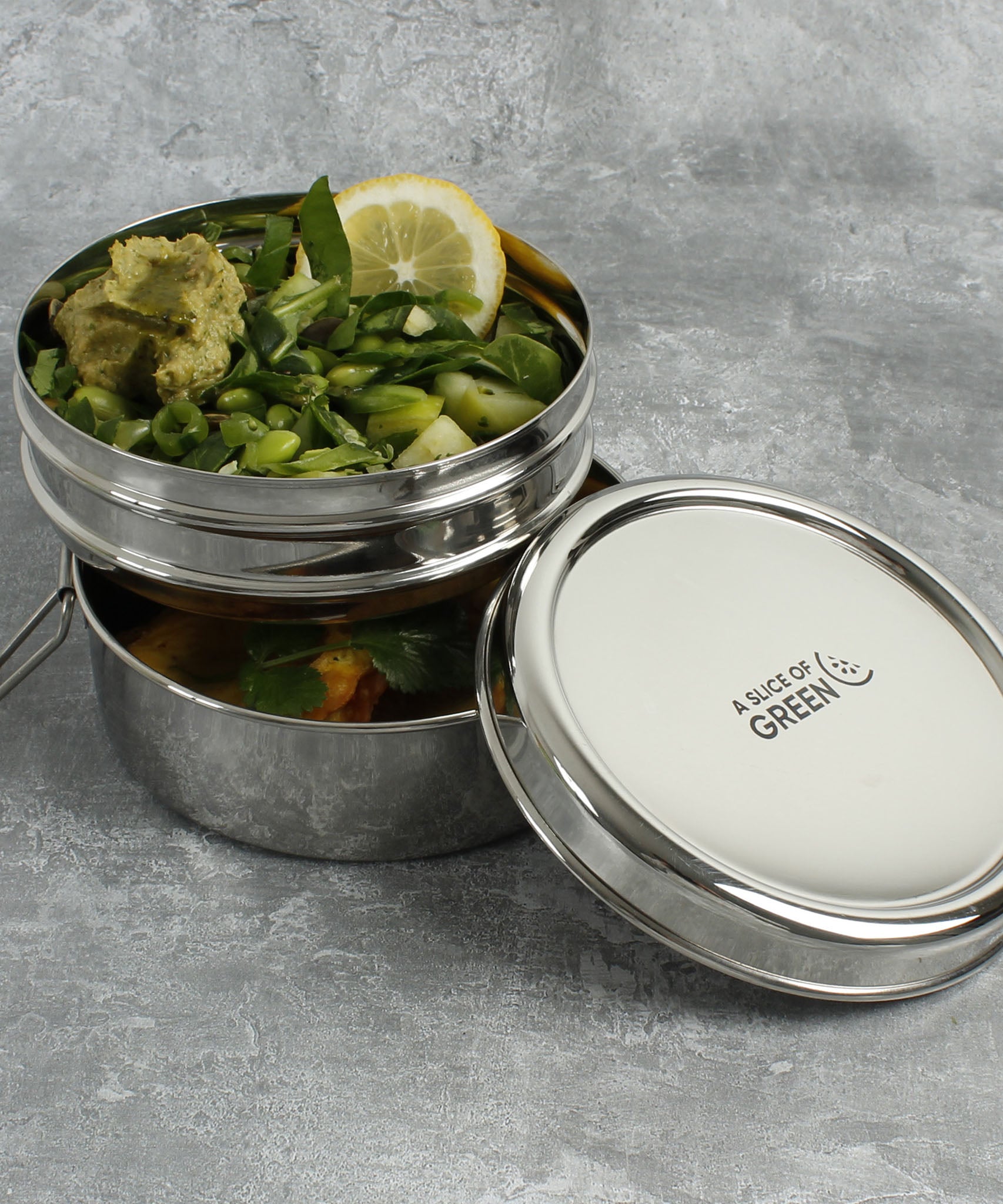 A close up of 2 of the tins from the stainless steel A slice of green chapra two tier round lunchbox  stacked on top of eachother 