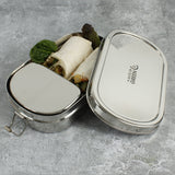 A close up of the A slice of green oval lunchbox with mini container showing various food items inside the main compartment