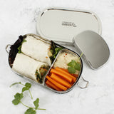 A top down image of the A slice of green oval lunchbox with mini container on a stone surface with different food items inside