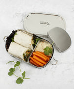 A top down image of the A slice of green oval lunchbox with mini container on a stone surface with different food items inside