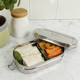 A slice of green oval lunchbox with mini container on a marble kitchen worktop