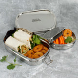 A slice of green oval lunchbox with mini container on a stone surface showing various food items in each container
