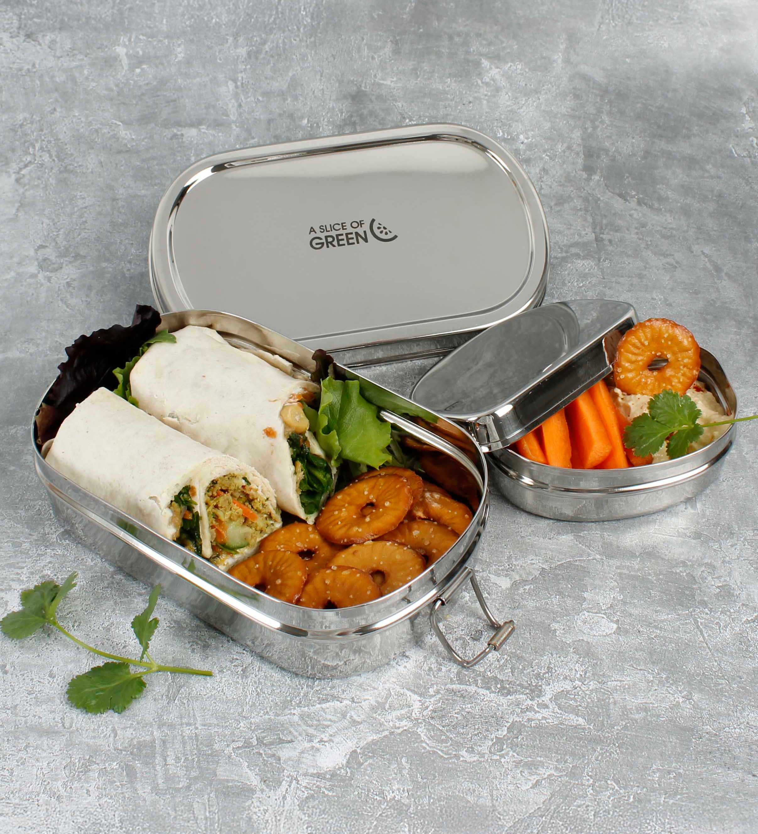 A slice of green oval lunchbox with mini container on a stone surface showing various food items in each container