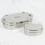A slice of green oval lunchbox with mini container on a stone surface with clip fasteners available at Babipur.