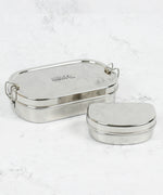 A slice of green oval lunchbox with mini container on a stone surface with clip fasteners available at Babipur.